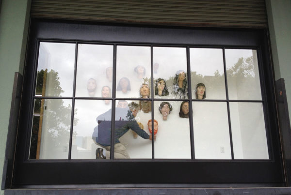 Frank Cole installs his students' self portraits in The Door, Roll Up Project