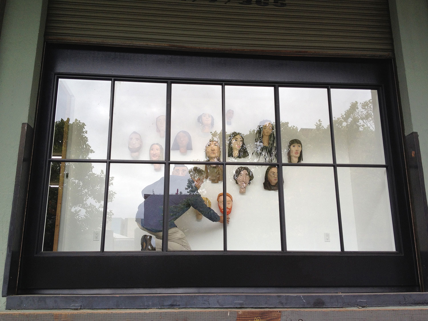Frank Cole installs his students' self portraits in The Door, Roll Up Project